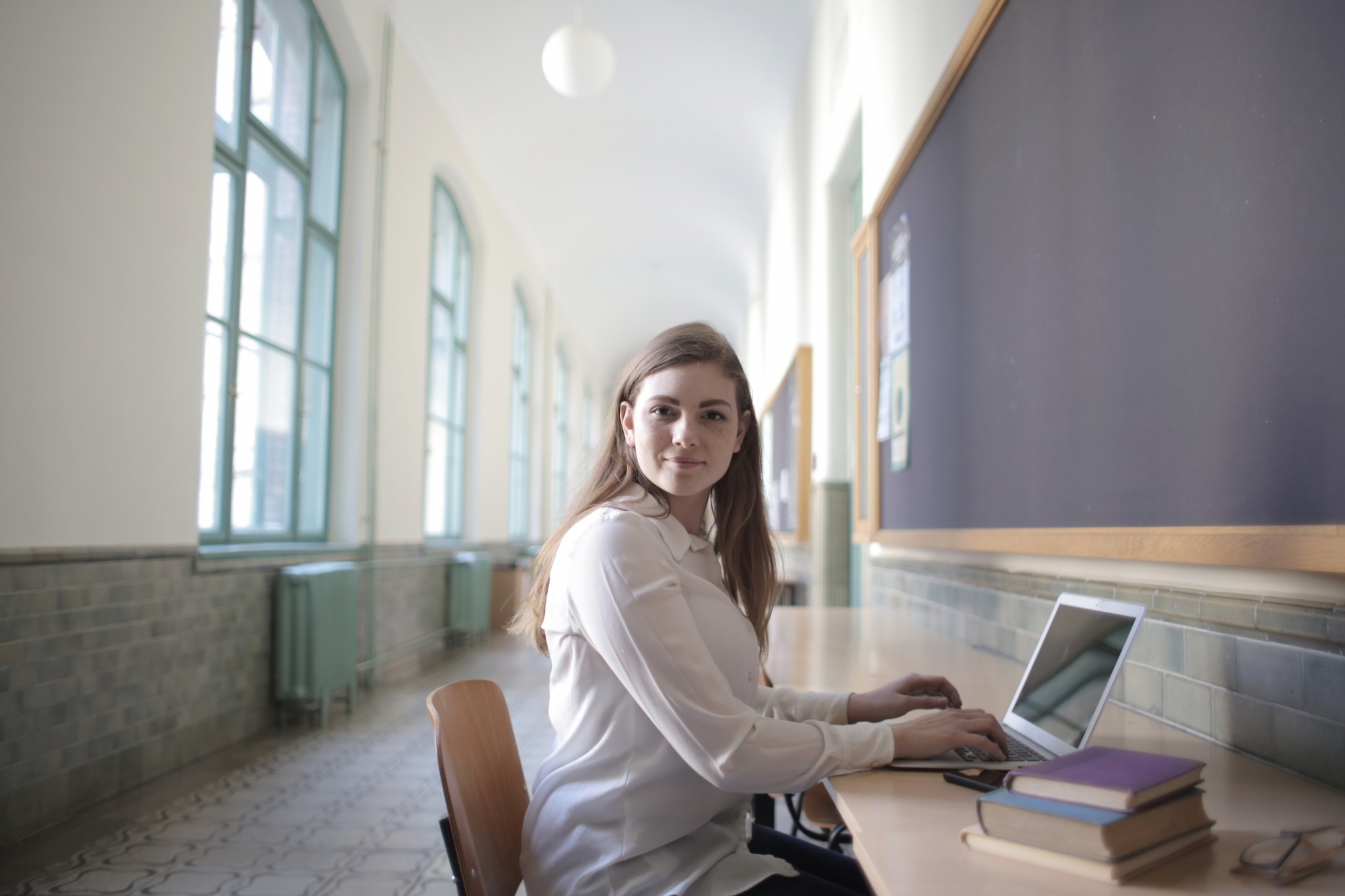 Female student typing on laptop in hallway