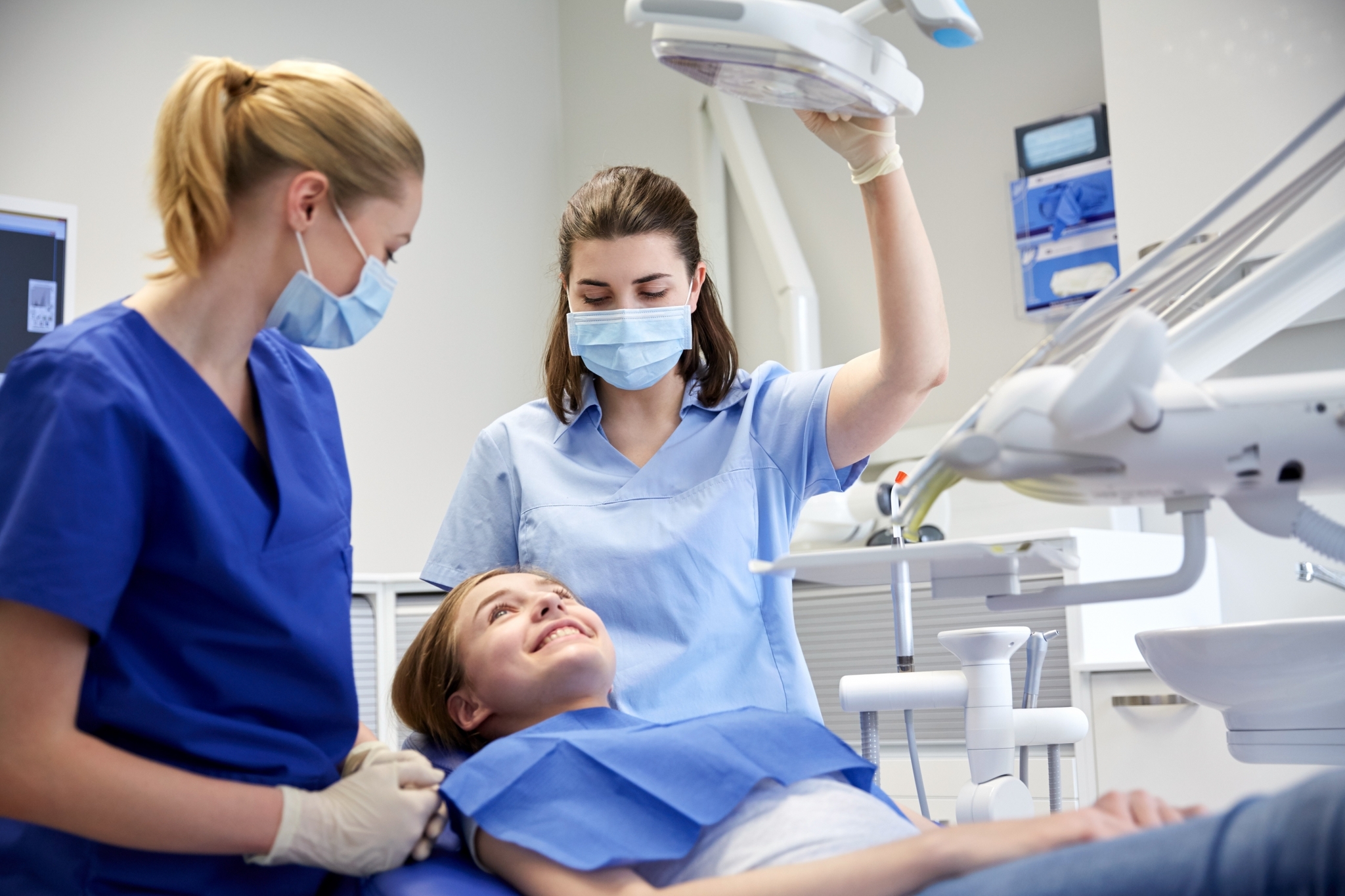 Two dental students in blue scrubs working with a patient
