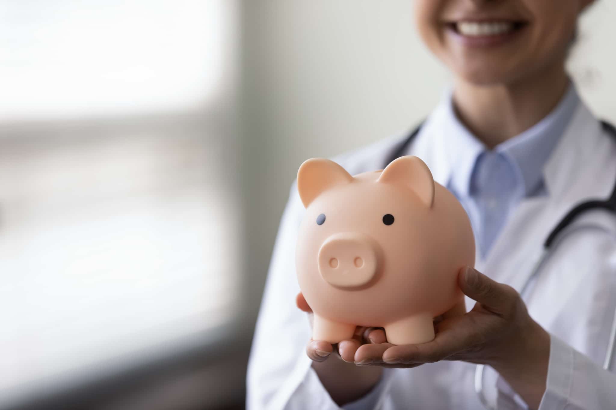 Medical professional holding a piggy bank