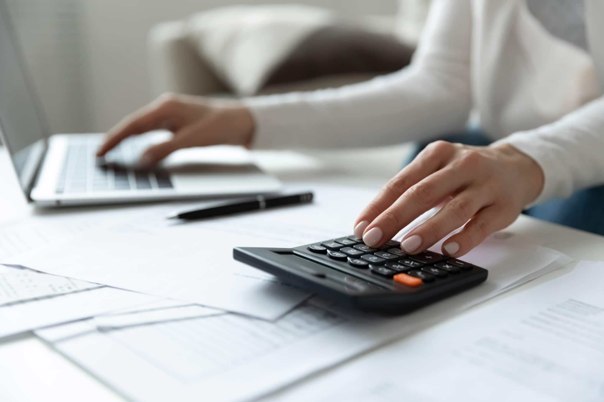 Close up of woman using a calculator and laptop