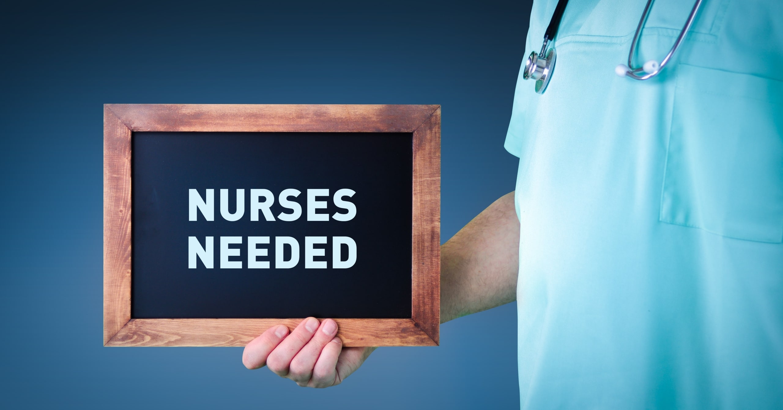 Nurse in scrubs holding a nurses needed sign