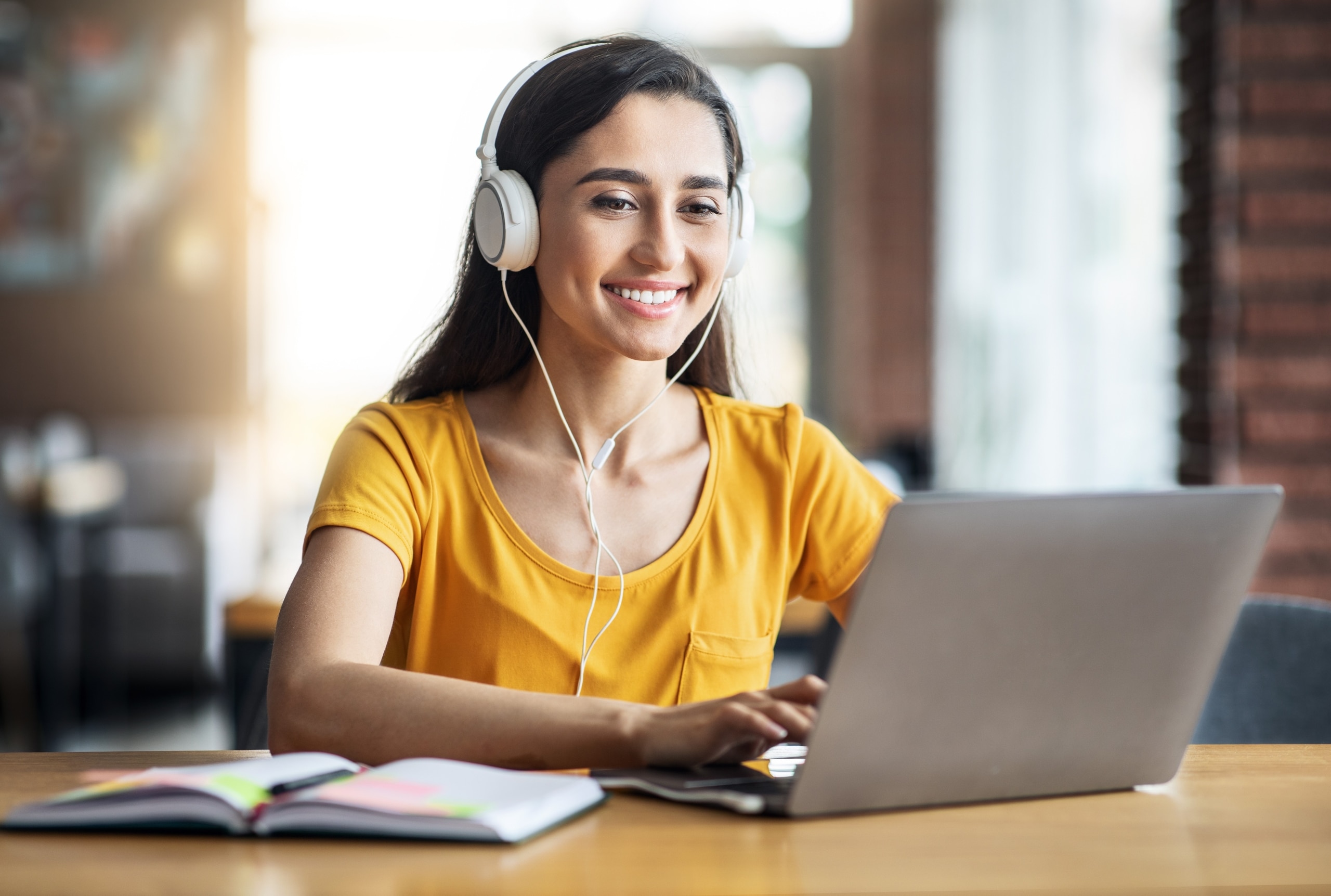 Smiling young woman wearing headphones and using a laptop