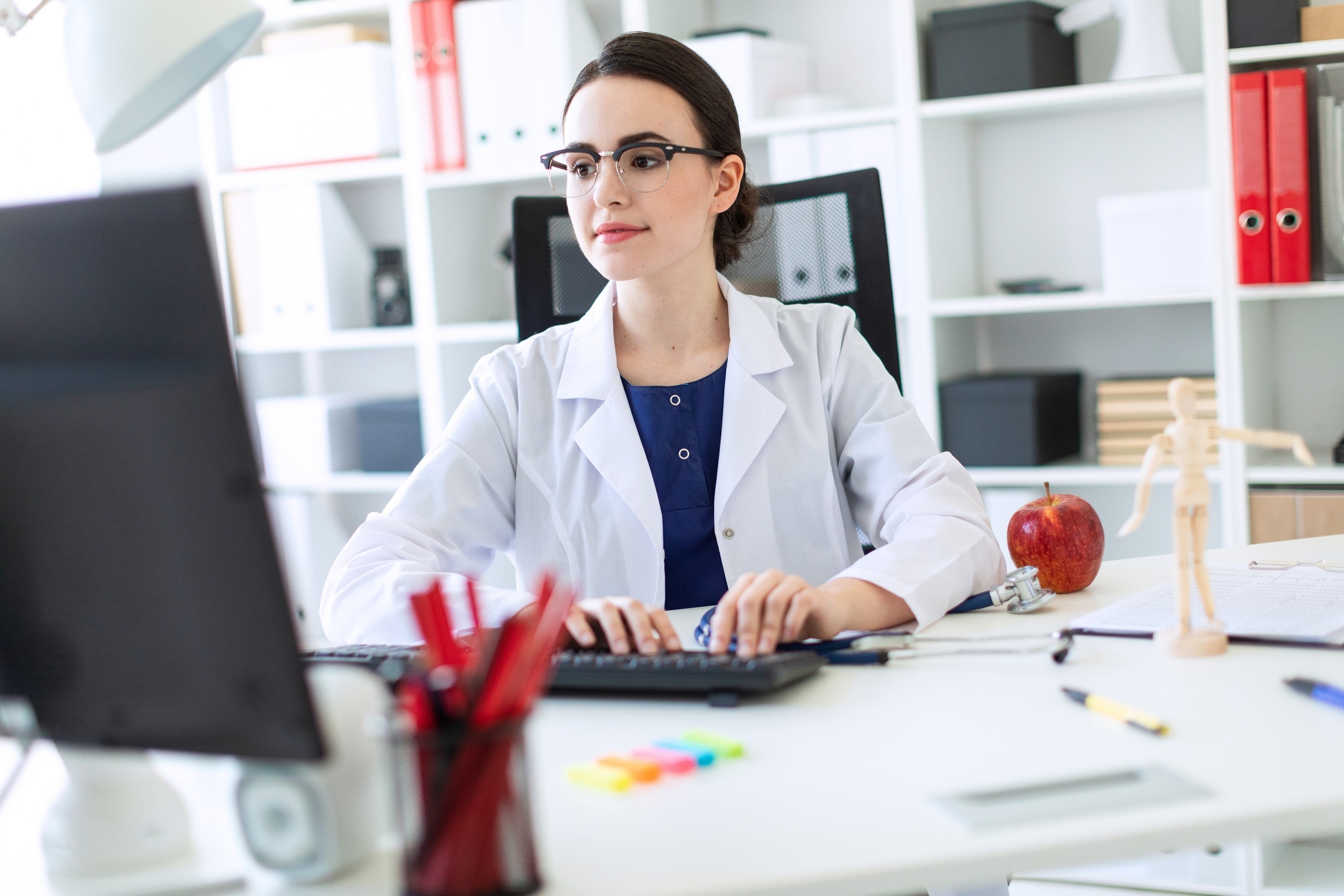 Young medical professional in glasses using a computer