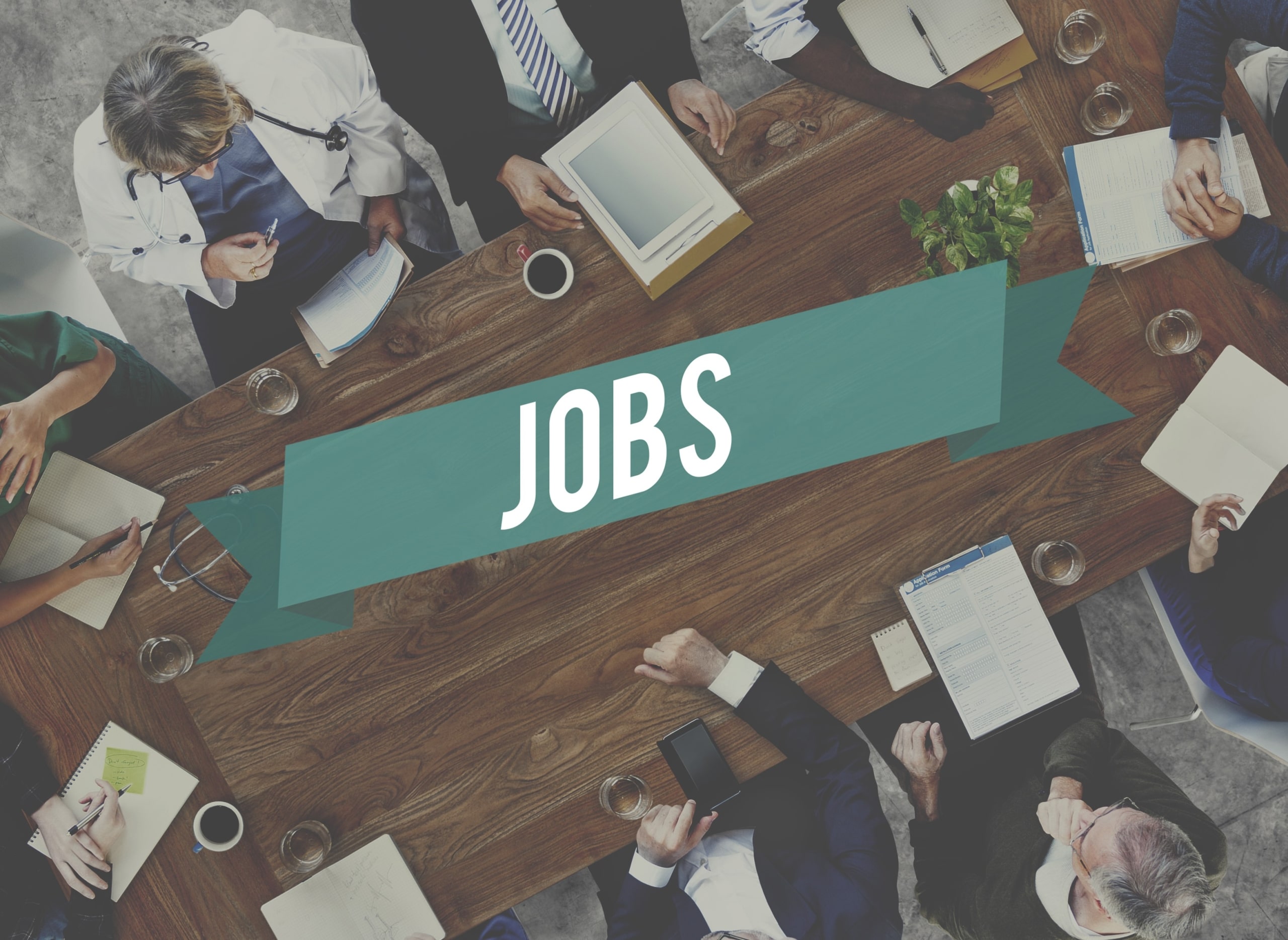 Aerial view of medical professionals sitting around a table that says JOBS