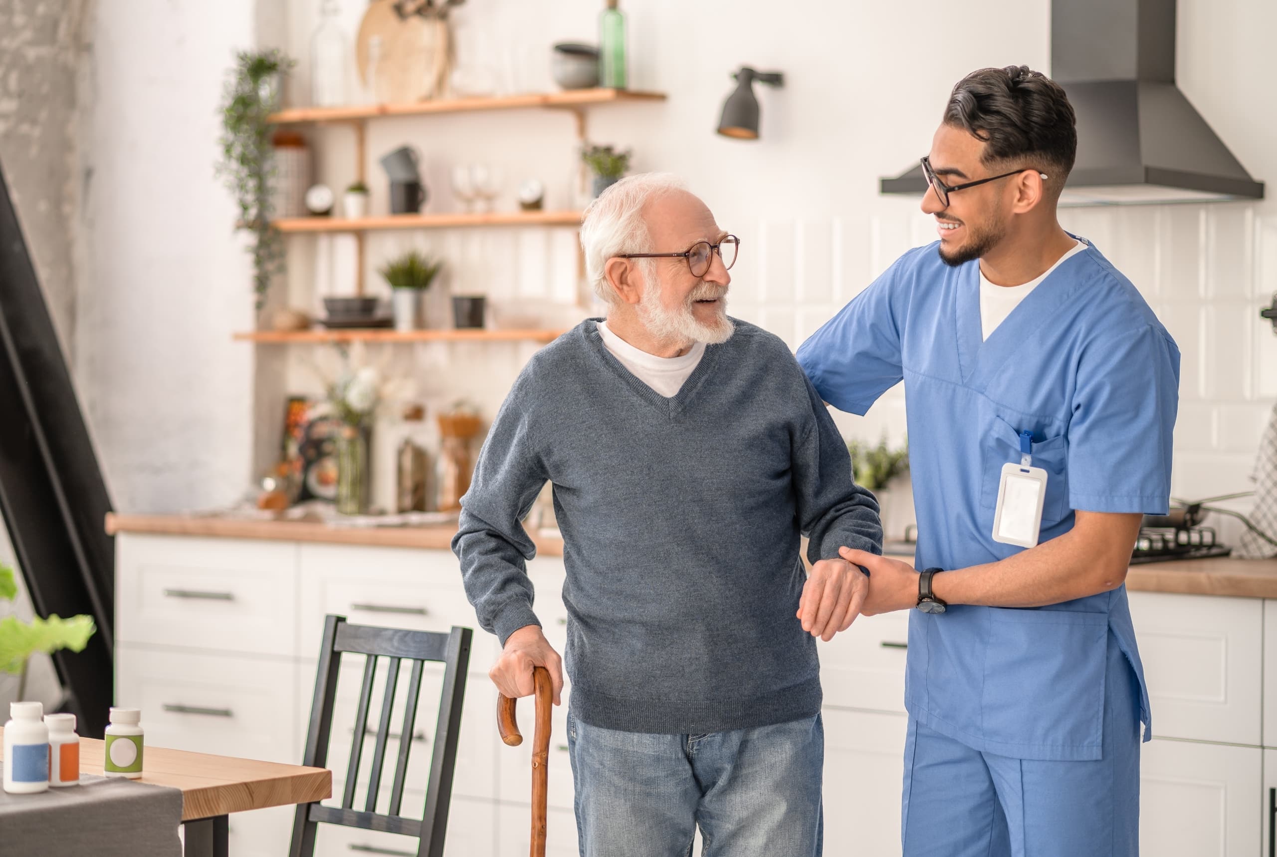 Male Latin nurse assisting an elderly man with a cane