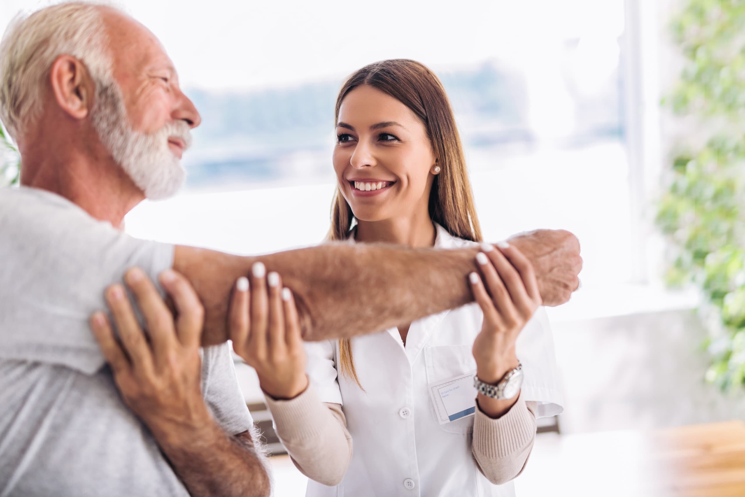Physical therapy professional helping an older man stretch