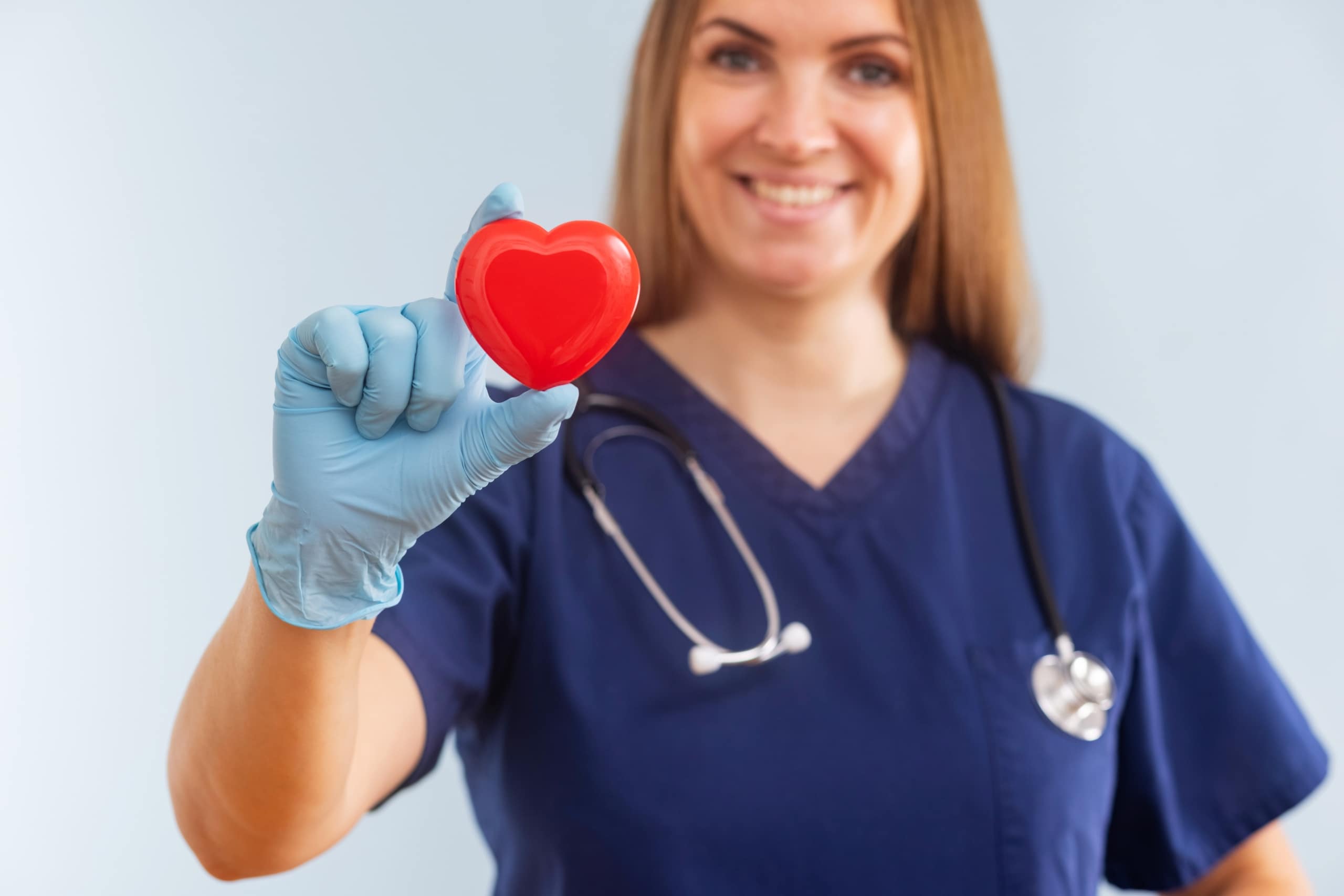 Nurse in scrubs holding a small model heart