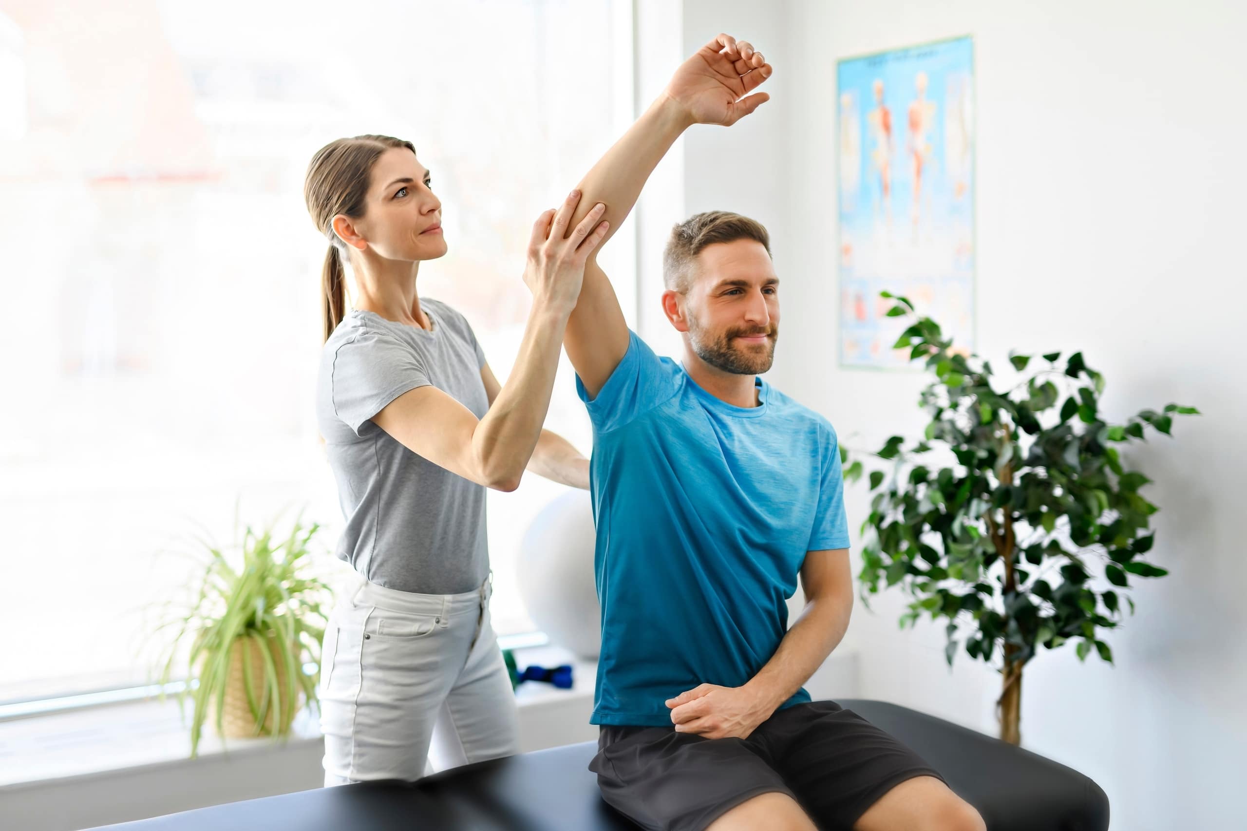 Physical therapy professional helping a man stretch at a clinic