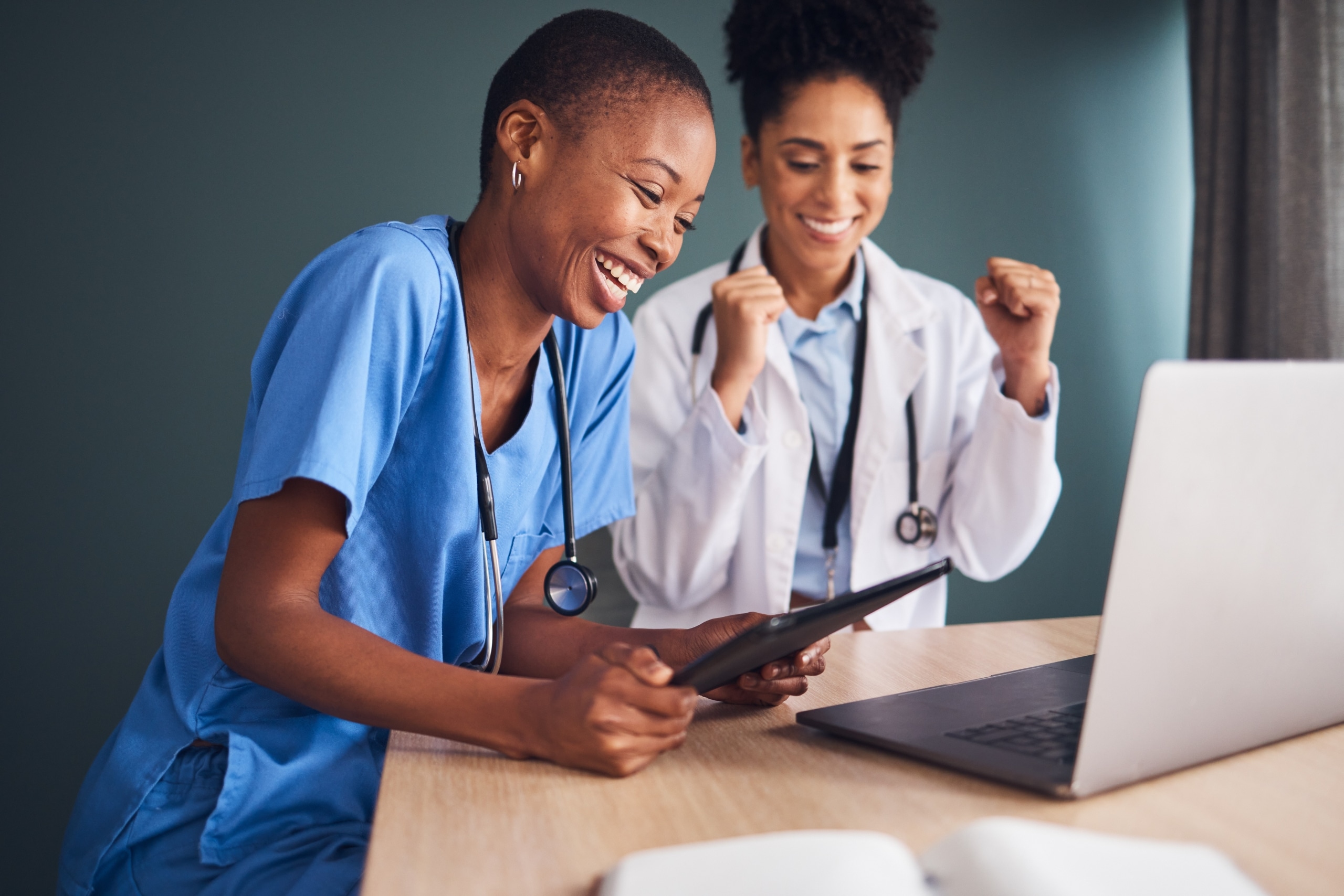 Two smiling medical professionals using a laptop