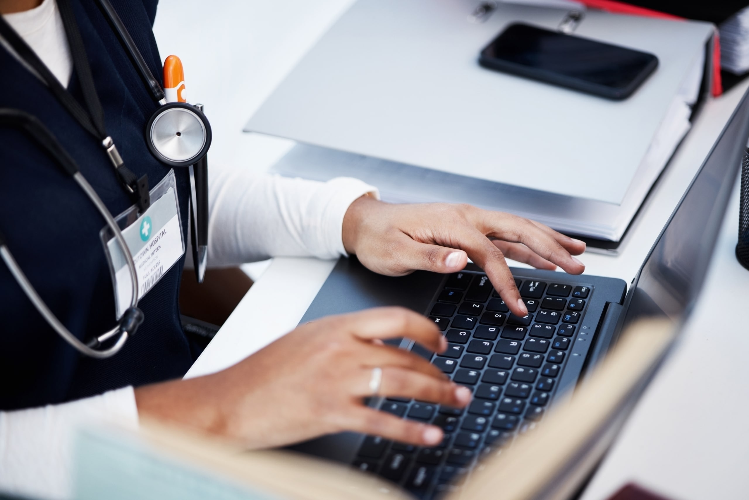 Close up of a nurse typing on a laptop