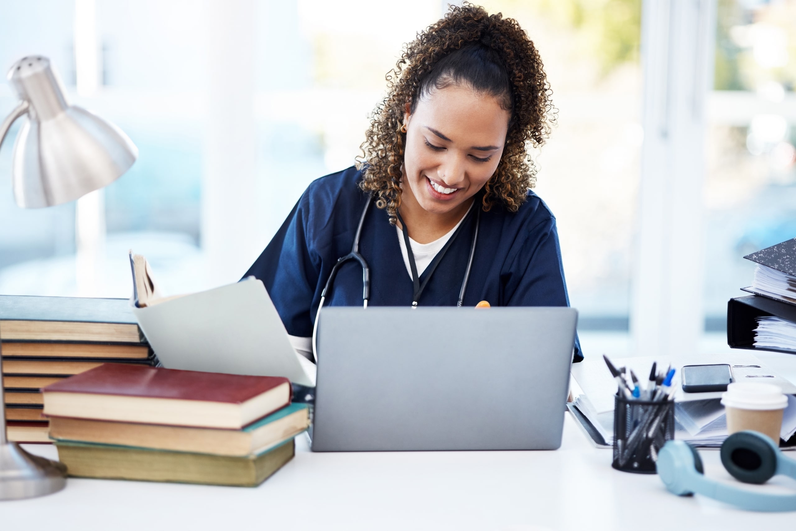 African-American nurse using a laptop and looking at textbooks