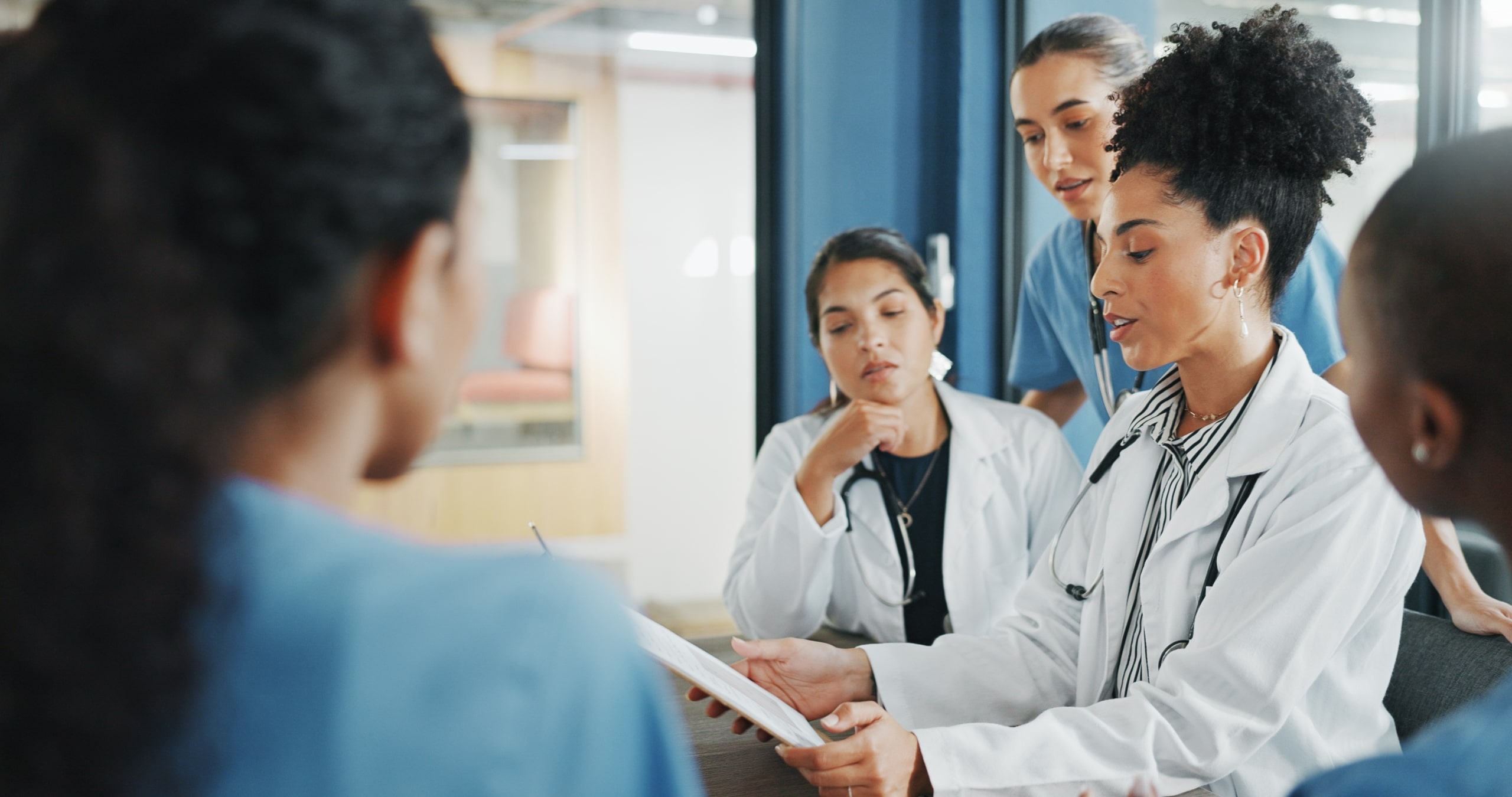 Diverse medical professionals looking at a clipboard in a meeting