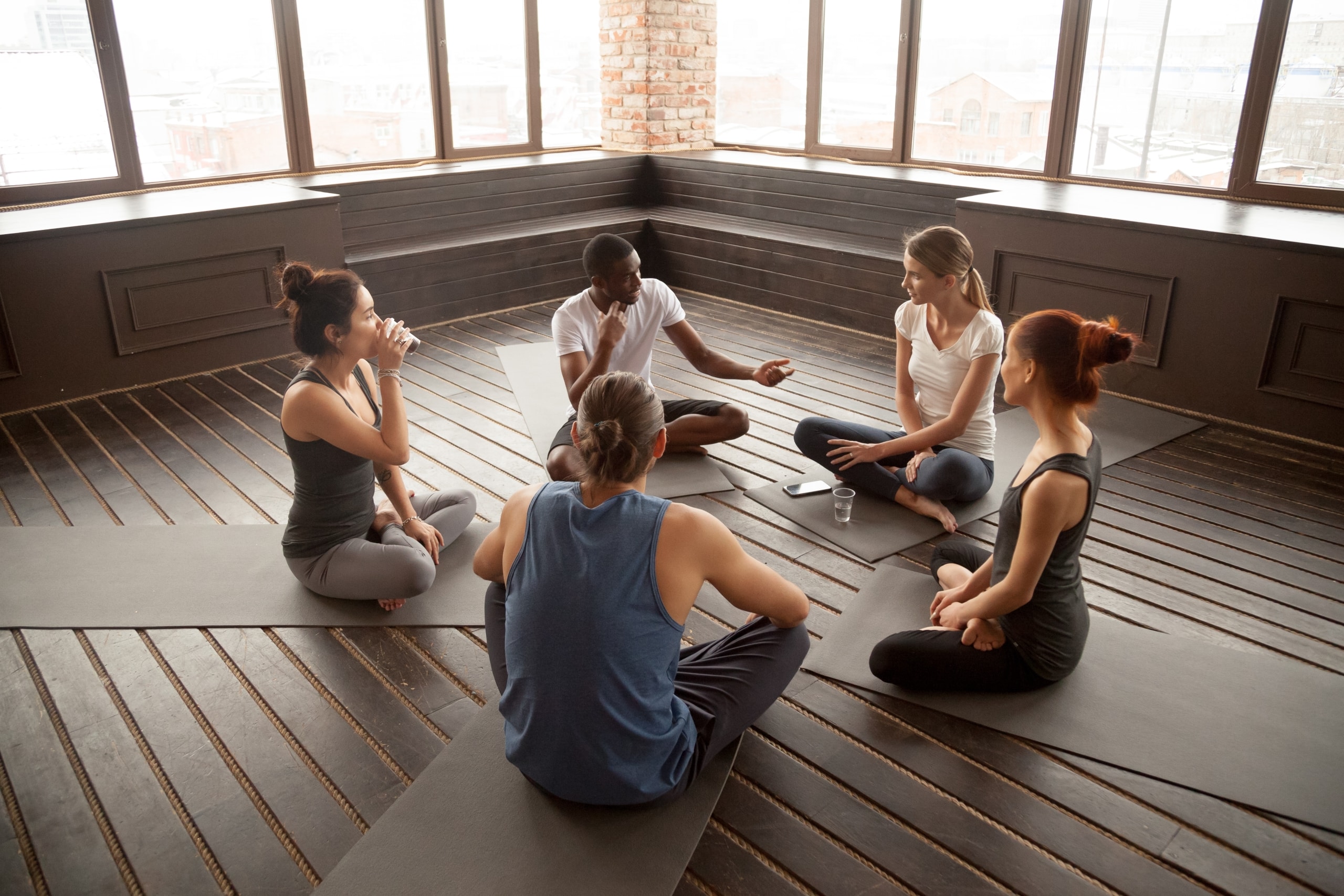 Diverse group of people sitting in a circle with their yoga instructor