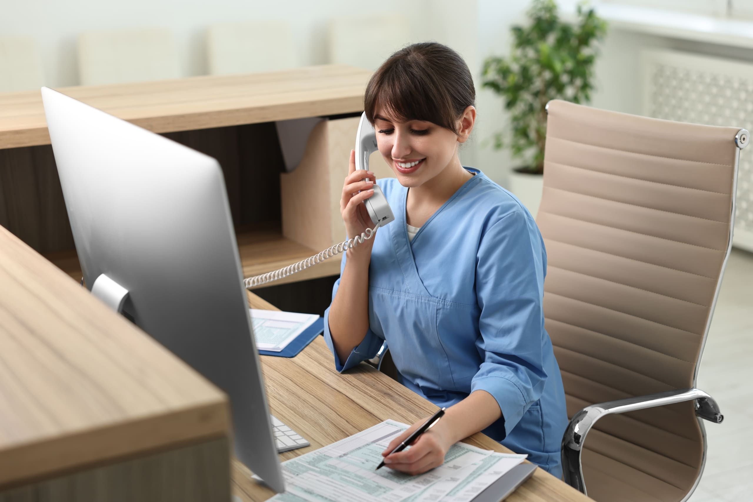Smiling medical professional using a phone and taking notes