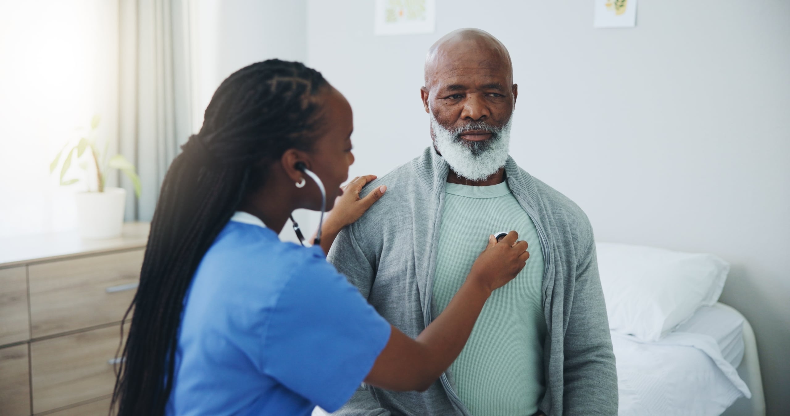 African-American medical professional listening to a senior patient's heartbeat