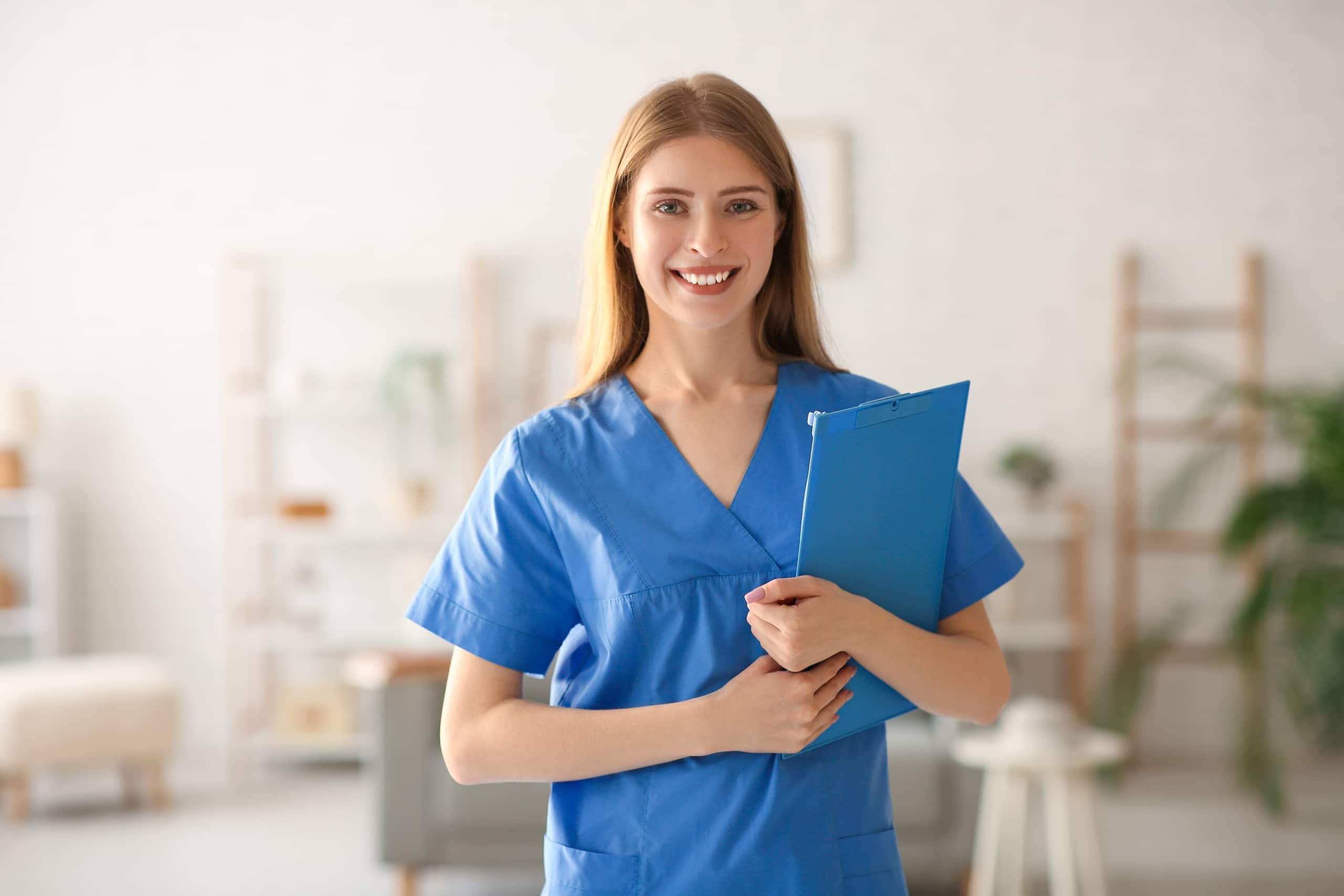 Female medical professional in scrubs holding a clipboard