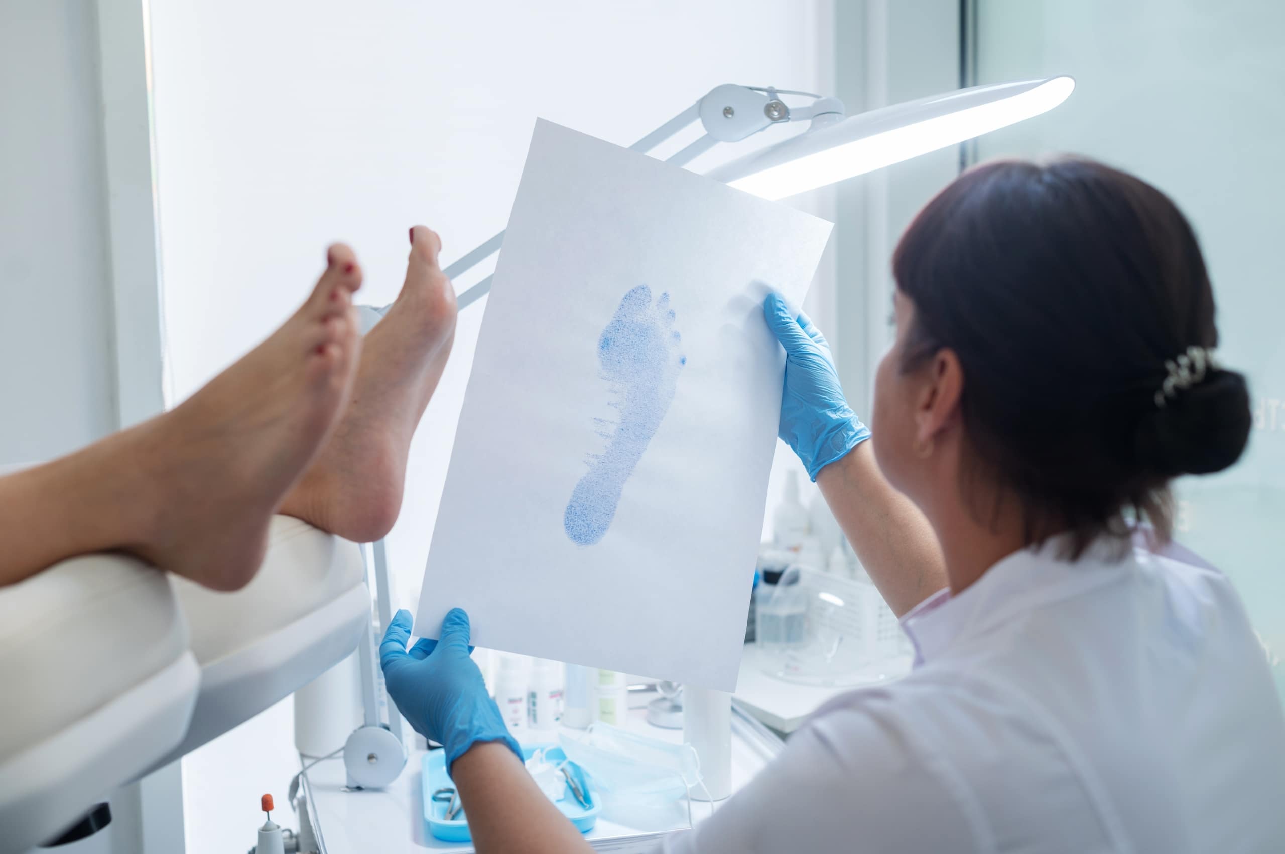 Medical professional looking at a patient's footprint in a podiatrist office