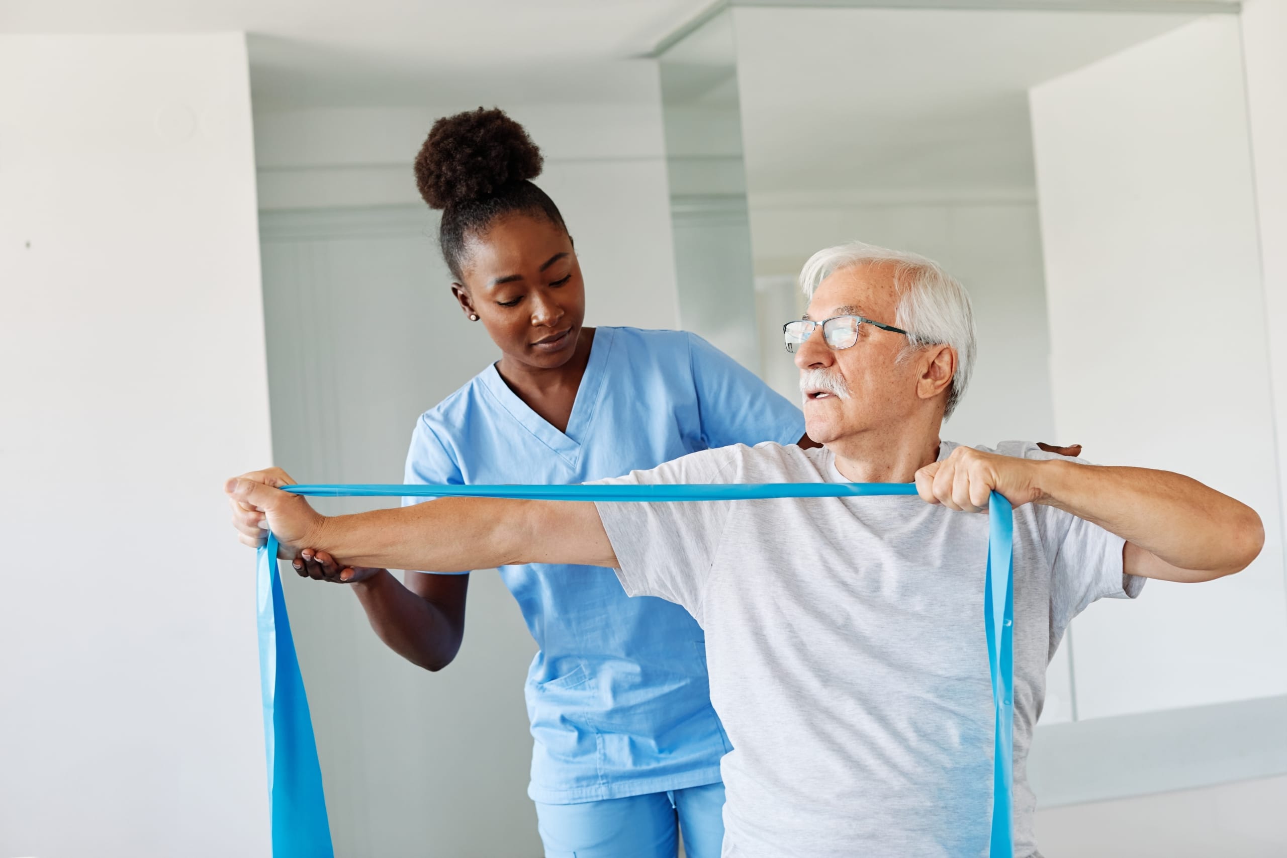 African-American medical professional helping a man use exercise bands