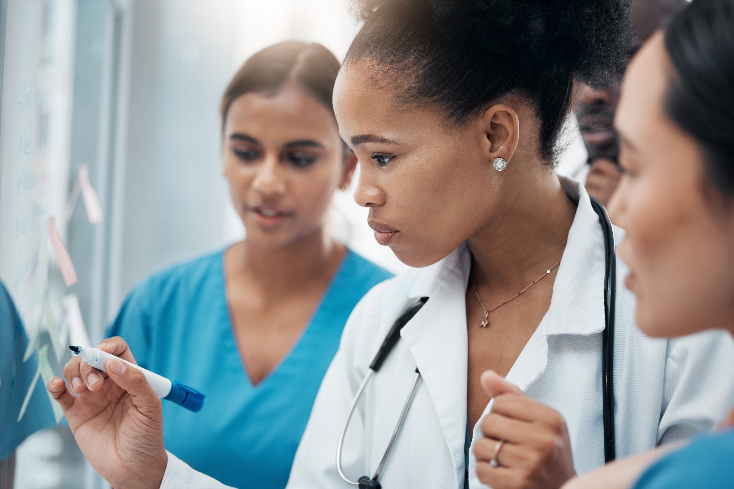 Diverse medical professionals writing on a whiteboard