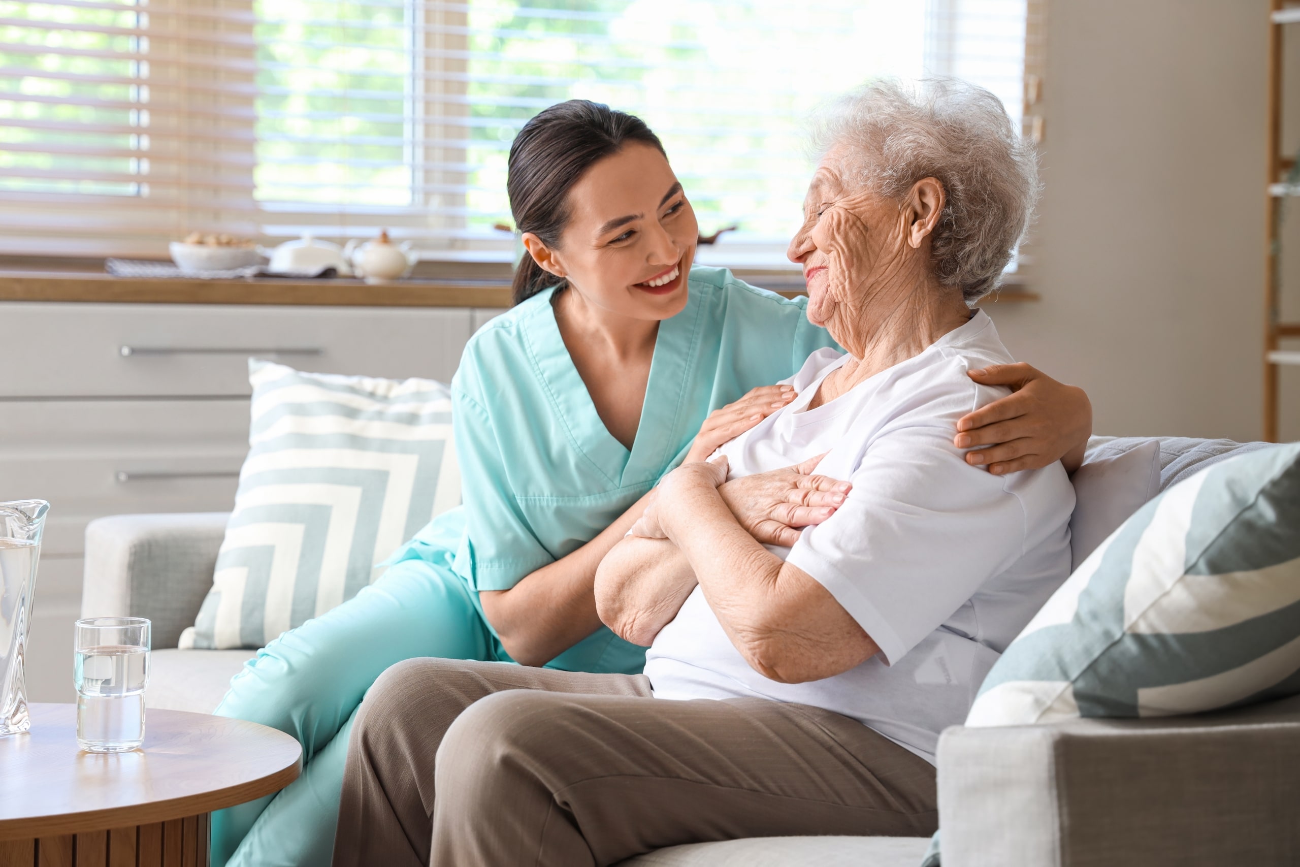 Medical professional laughing with an elderly patient on a sofa