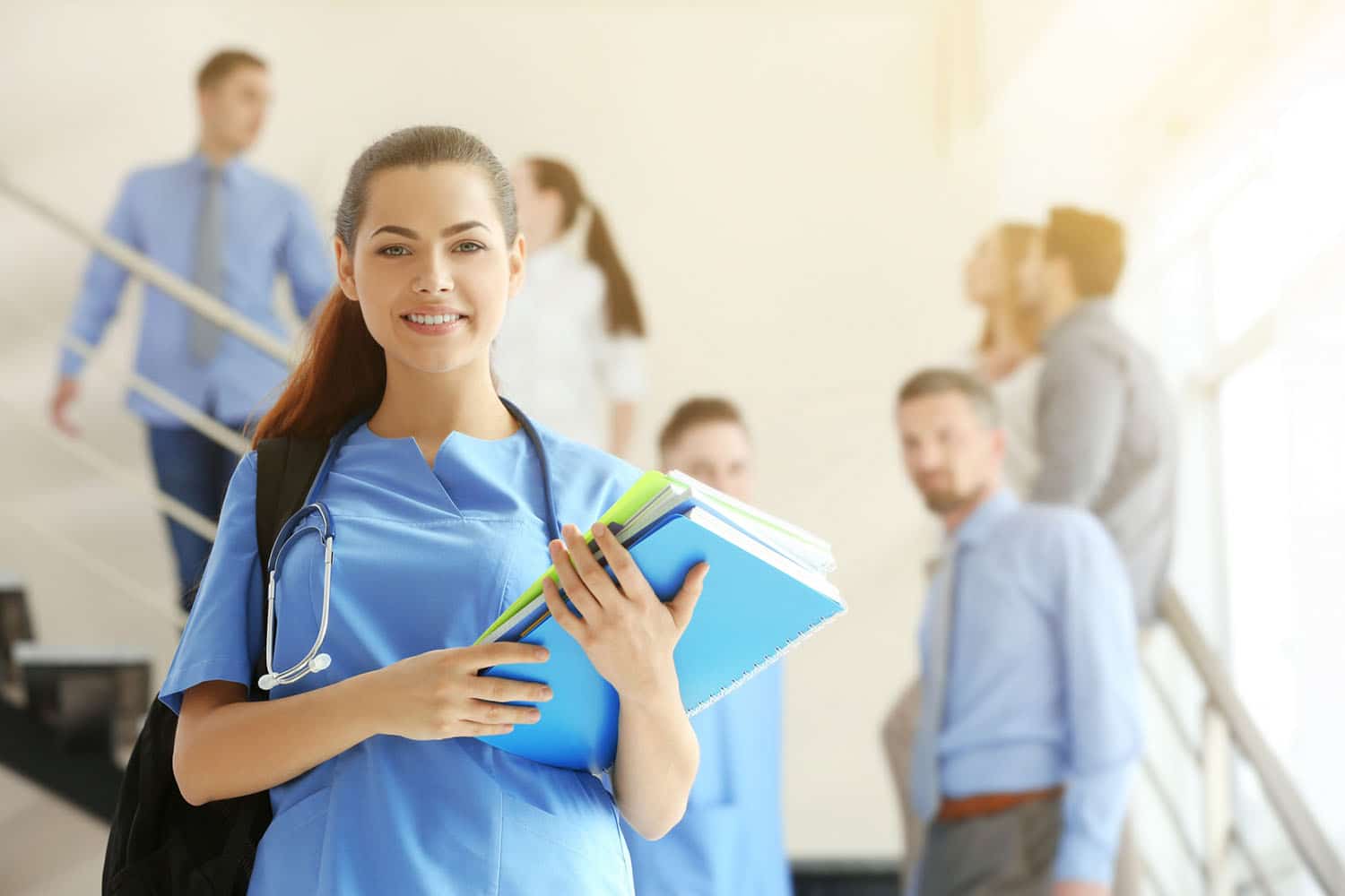 Nursing student holding binders and standing on a stairwell