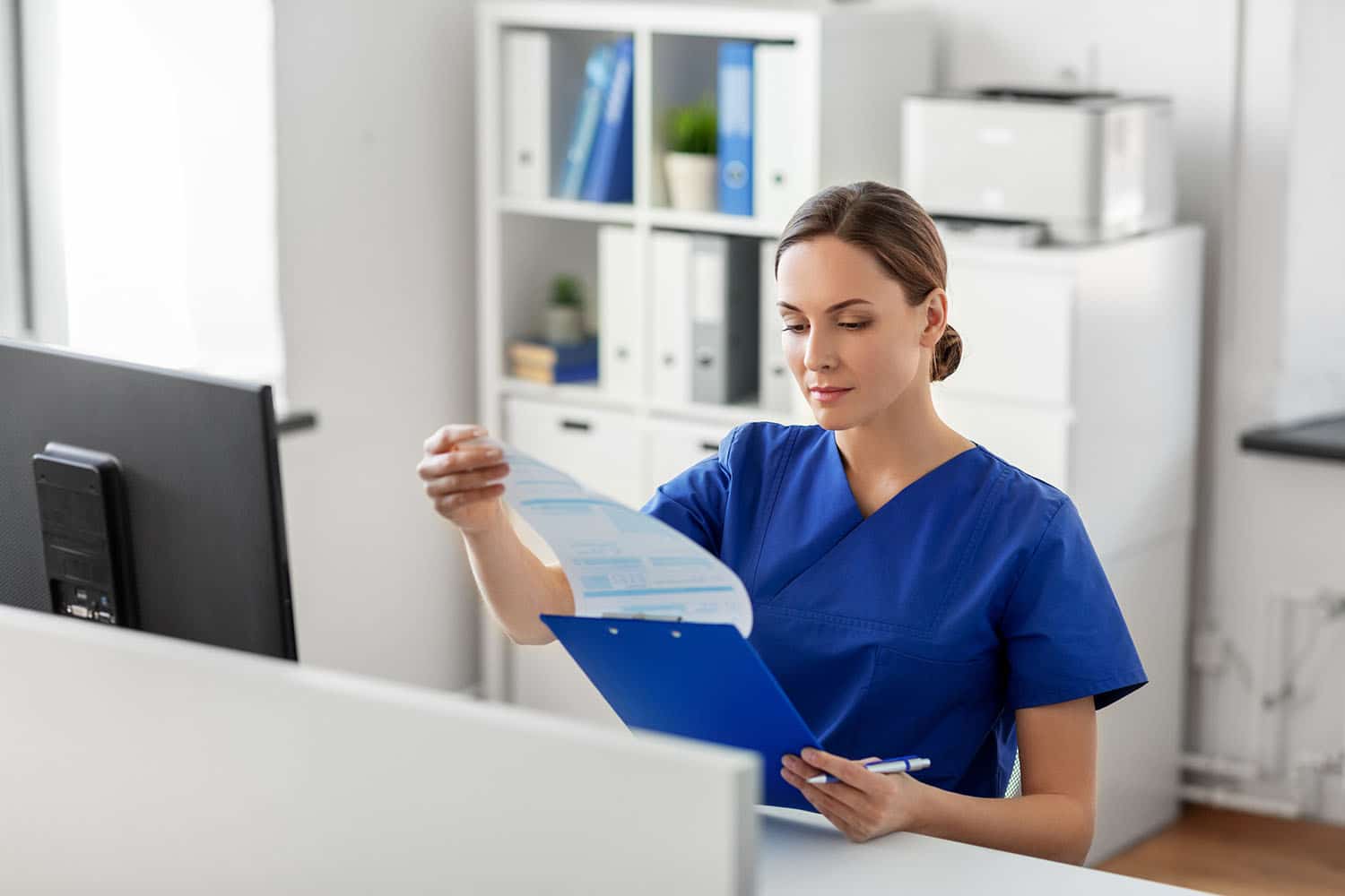Blonde woman in scrubs consulting medical charts