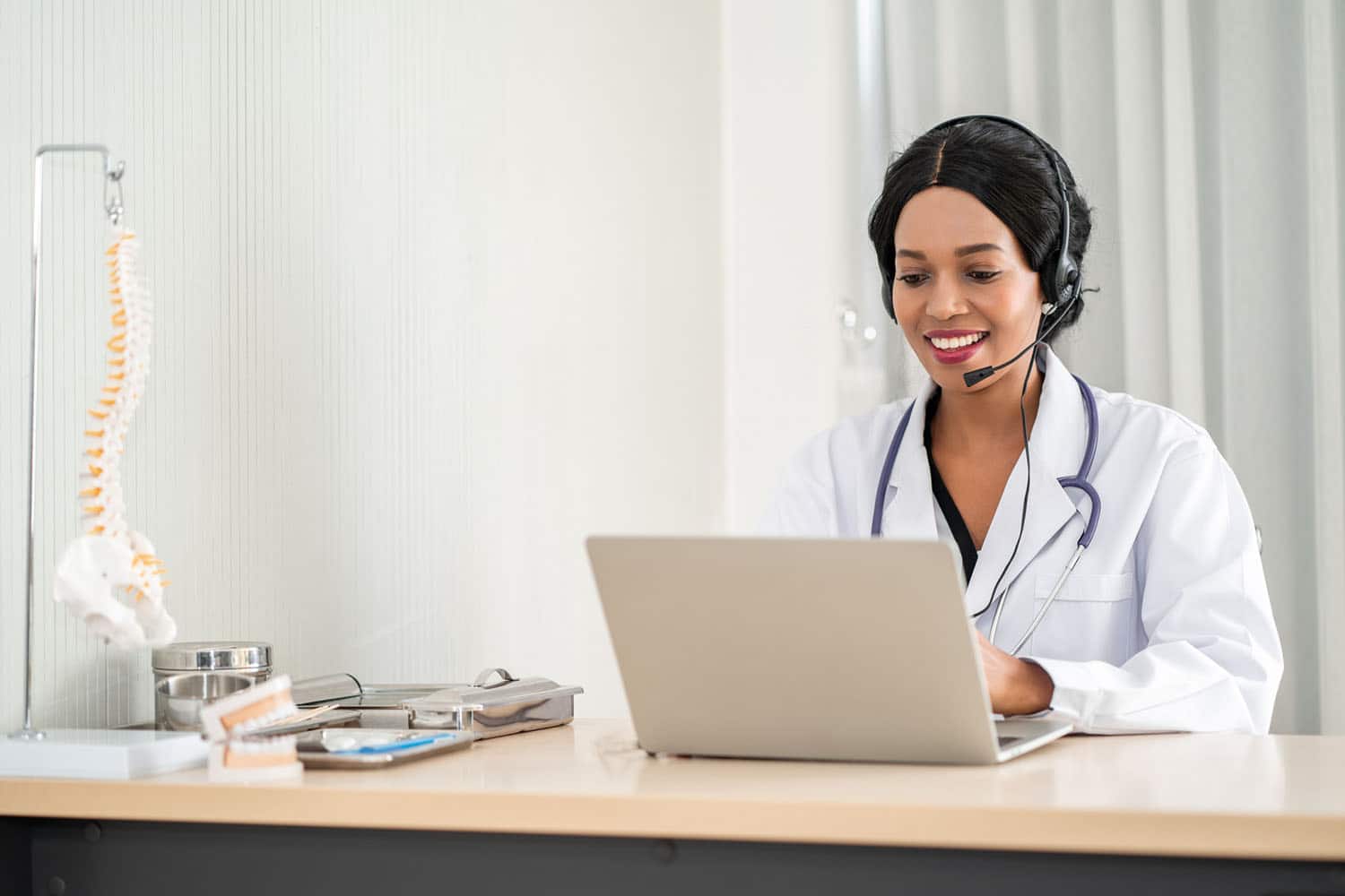 Medical professional wearing a headset and using a laptop