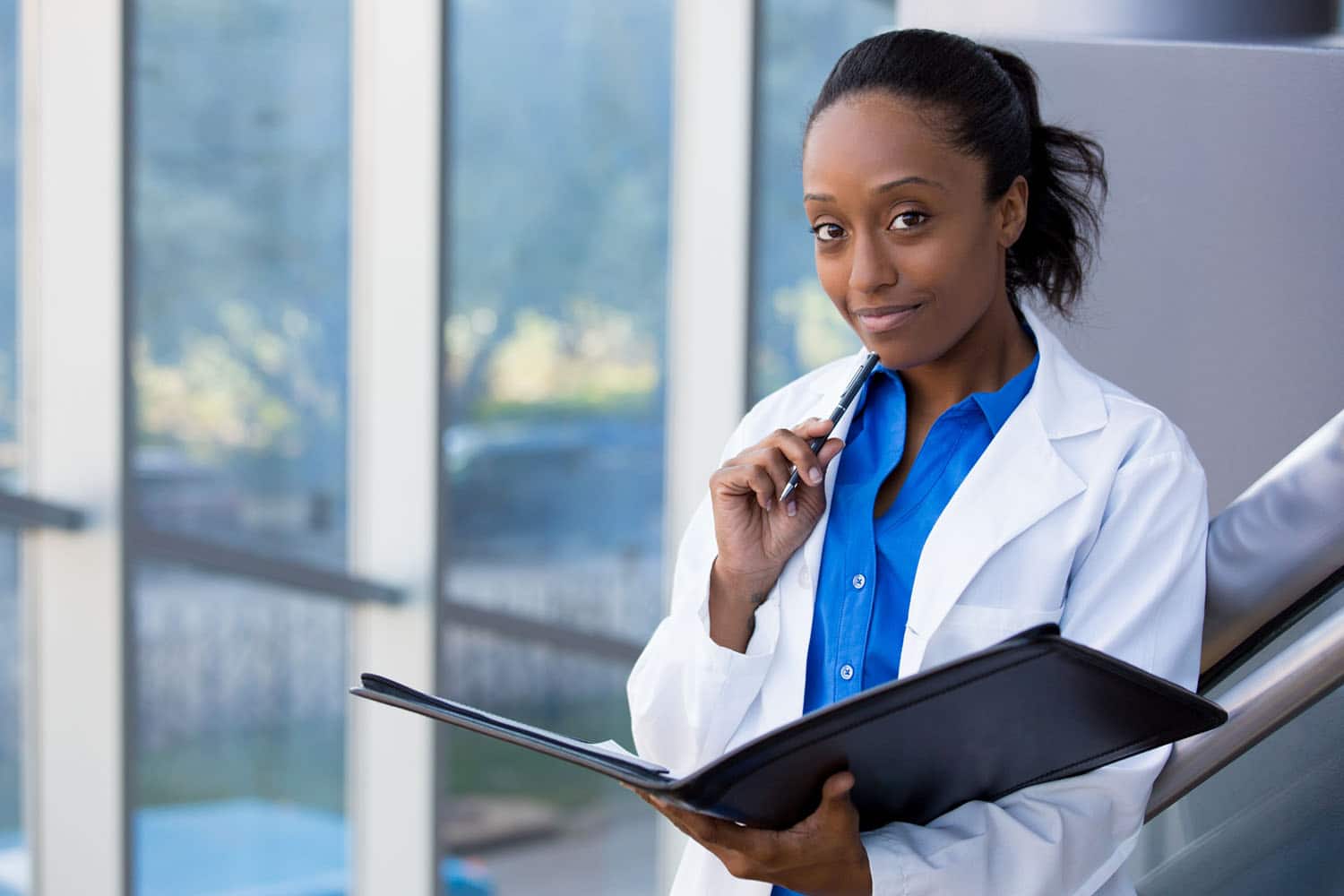 African-American woman in a lab coat outside of a hospital